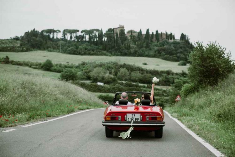 Just married couple driving in a red cabriolet in Italy